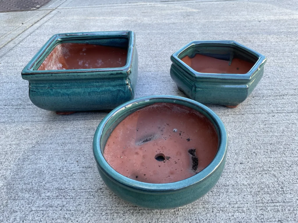 Handmade green-glazed bonsai pots from Bát Tràng, one with a centre drainage hole