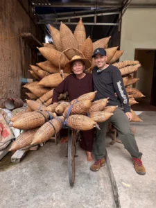DH Garden Centre owner sitting with master weaver Lương Sơn Bạc among handwoven bamboo baskets in Hung Yen, Vietnam