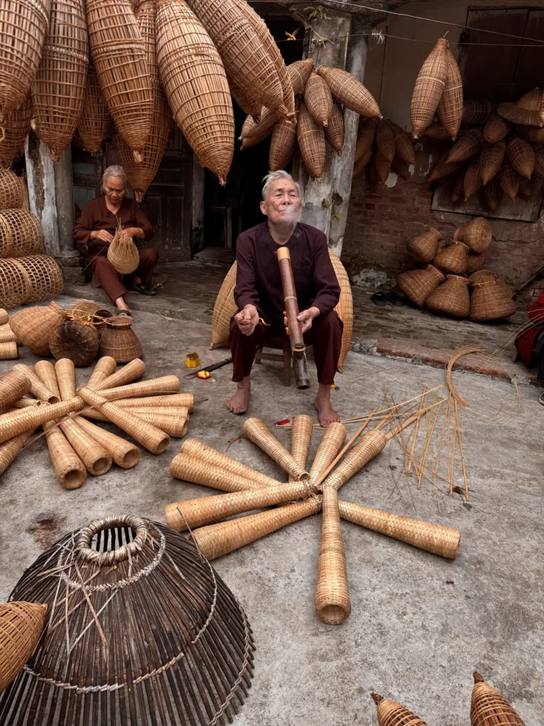 Master weaver Lương Sơn Bạc weaving bamboo fish-trap baskets in his village courtyard in Hung Yen, Vietnam