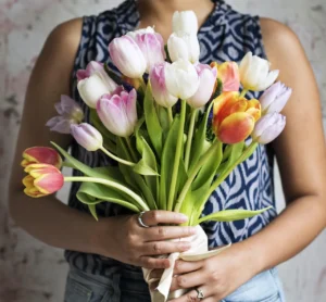 Hands holding a bunch of freshly cut pink, white, and orange tulips